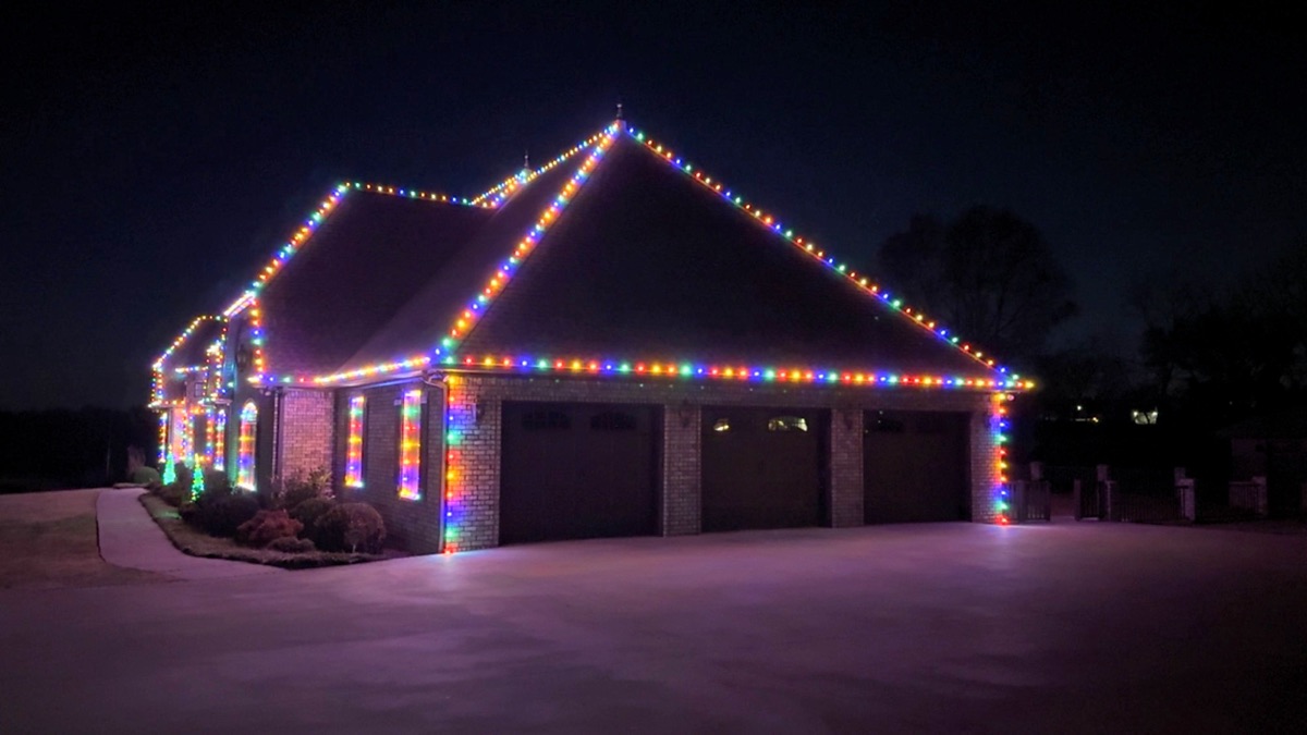 Brick home and three-car garage outlined in multicolor lights